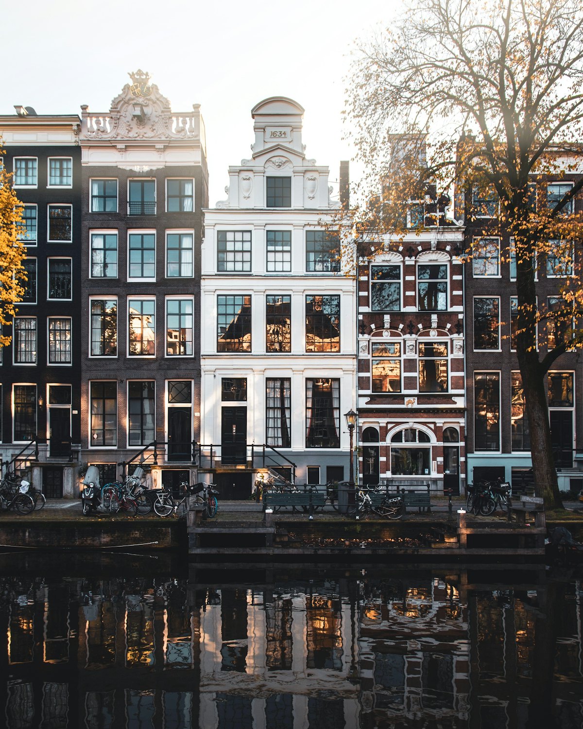 Grachtenpanden in Amsterdam met herfstbomen, weerspiegeld in het water