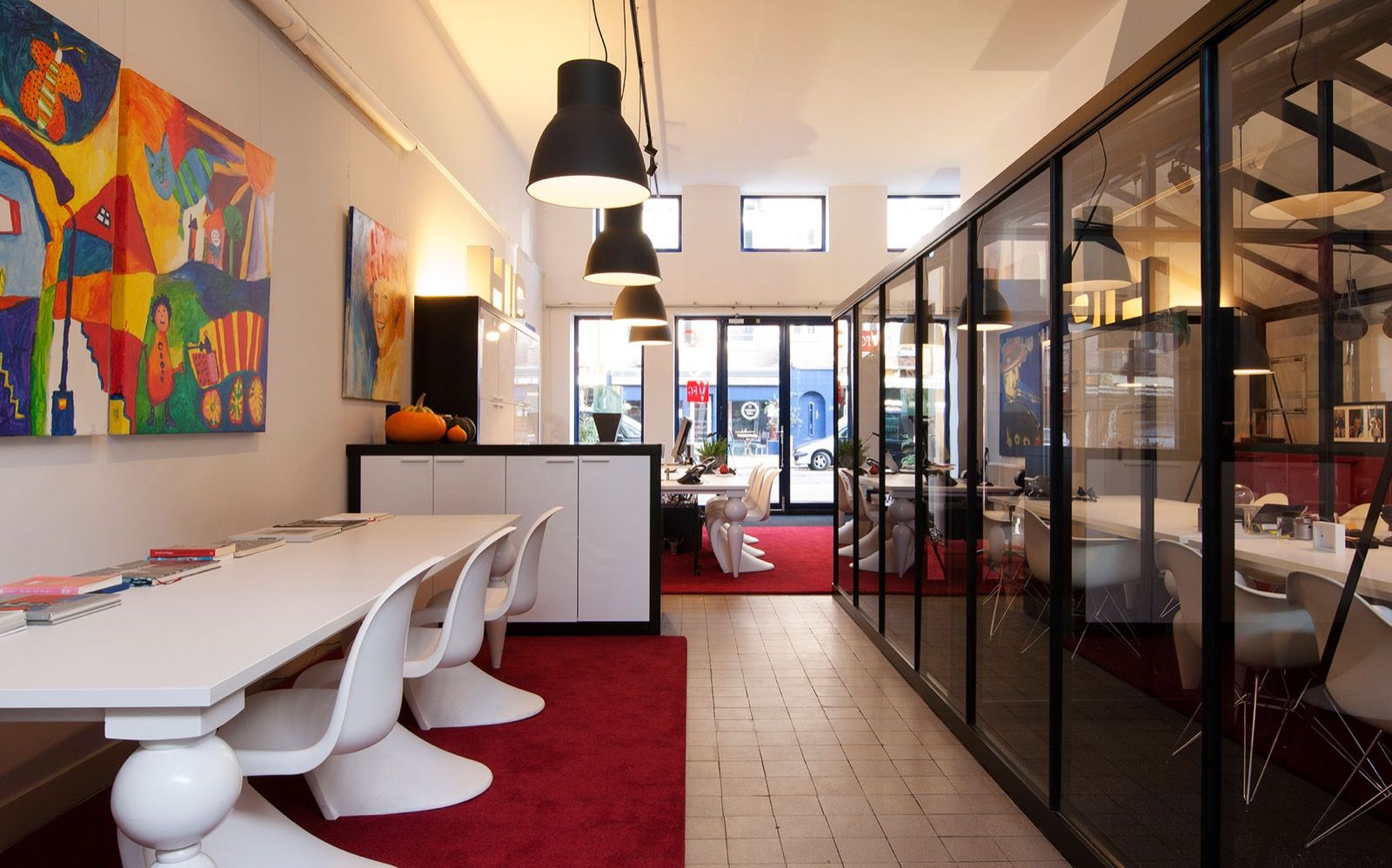 Het kantoor met kunst aan de wand, rood tapijt en een glazen spreekkamer
